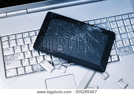 A Silver Laptop With A Broken Keyboard, Tablet With A Cracked Display And Black Phone. A Close-up Pi