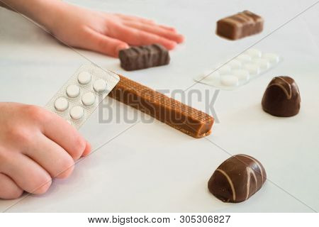 Child Holds In Hand A Package Of Pills. Tablets Are Among The Candies. Concept Of Dangerous Domestic