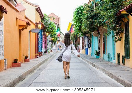 Beautiful Woman On White Dress Walking Alone At The Colorful Streets Of The Colonial Walled City Of