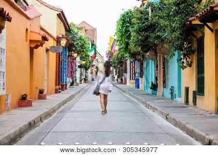 Beautiful Woman On White Dress Walking Alone At The Colorful Streets Of The Colonial Walled City Of