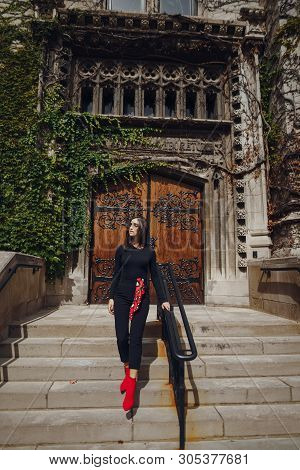 Stylish Brunette Standing Next To The Entance To A Building