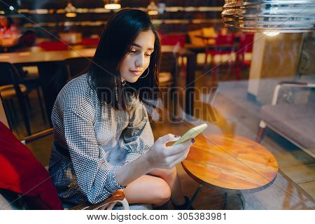 Brunette Girl Using Her Cellphone To Reach A Friend