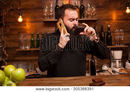 Bearded Young Batender Talking On The Phone Taking Care Of His Business.