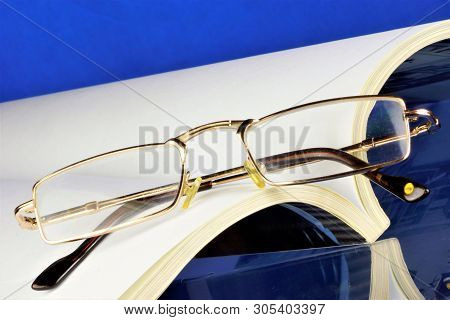 Magazine -- Printed Periodical And Reading Glasses, On A Creative Background. The Journal Has A Perm
