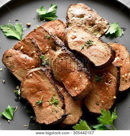 Close Up Of Grilled Sliced Beef Liver On Plate Over Black Stone Background. Cooked Liver(offal) From