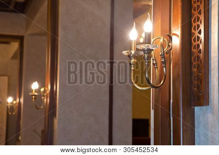Retro Copper Candlestick Hanging On The Wall. Vintage Golden Candlestick With Light Bulbs. Gold Wall