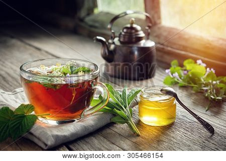 Several Medicinal Plants And Herbs On Table, Healthy Herbal Tea Cup, Honey Jar And Vintage Copper Te