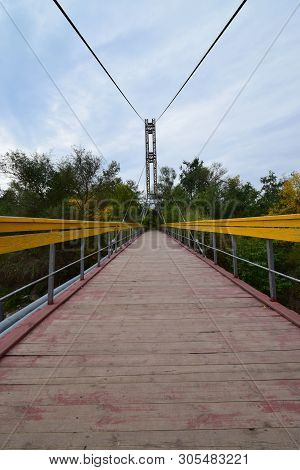 View Of The Suspension Bridge With Yellow Railings And Cables Across The River On Mount Kizilovka In