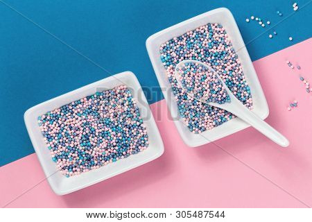 Colorful Nonpareils Cake Candy Sprinkles In Two White Rectangular Bowlsand Spoon On Pink Blue Backgr