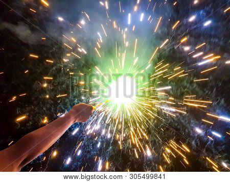 Hand Charki, A Hand Firework Emitting Circular Sparks In Black Background