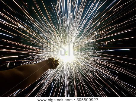 Hand Charki, A Hand Firework Emitting Circular Sparks In Black Background