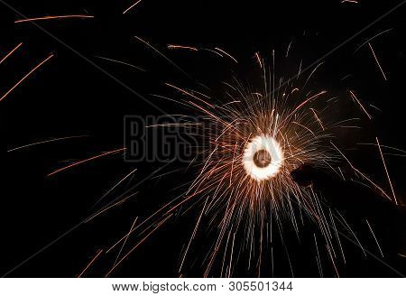 Hand Charki, A Hand Firework Emitting Circular Sparks In Black Background