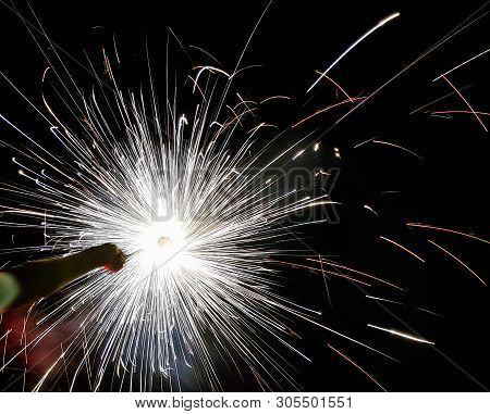Hand Charki, A Hand Firework Emitting Circular Sparks In Black Background