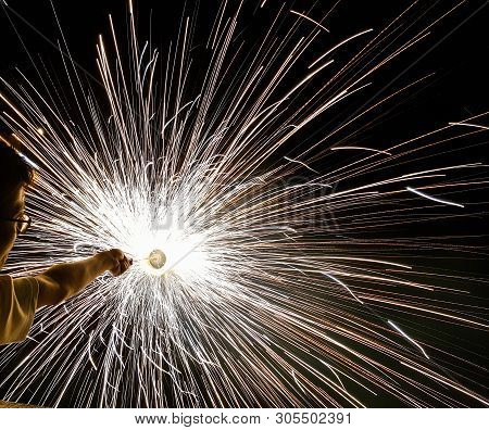A Man Holding Hand Charki, A Hand Firework Emitting Circular Sparks In Black Background