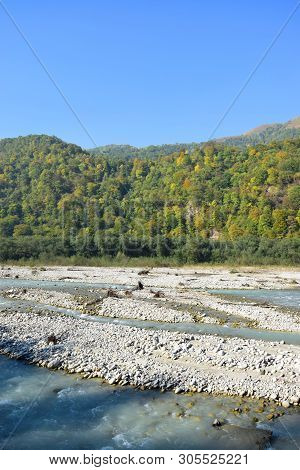 View Of The Fast Mountain River With Blue Water With Stones And Mountains With Green Trees In The Ch