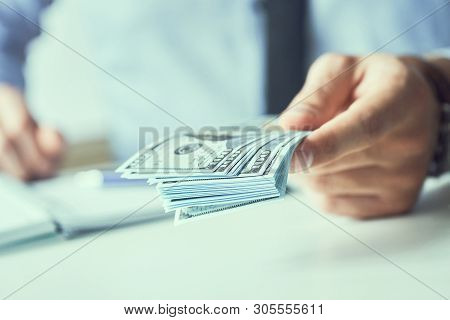 Man Giving Money Us Dollar Banknotes And Holding Cash In Hands. Money Credit Concept. Toned Picture.