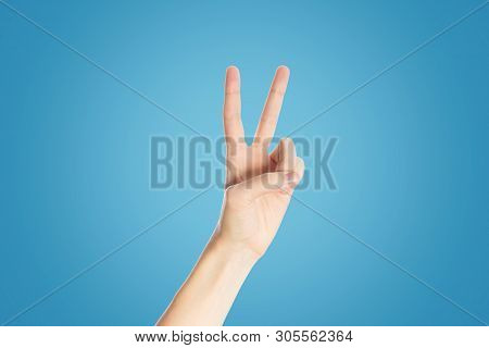 Positive Gesture On Blue Background. Hand Show Viktory Sign, Close Up