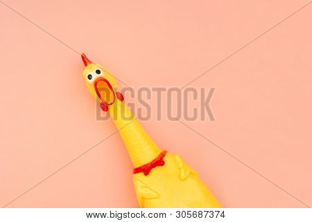 Creeping, Rubber Chicken Toy On A Pastel Pink Background. Rubber Toy Chicken That Screams Isolated O