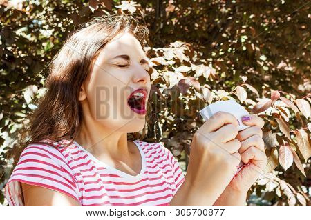 Front View Of A Single Girl Sneezing And Blowing In A Wipe Outdoors With A Green Background