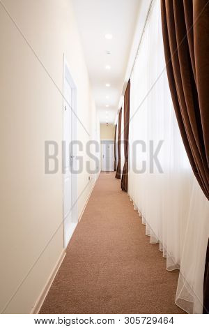 Bright Corridor With White Doors, Brown Carpet, White Tulle Curtains And Brown Curtains.