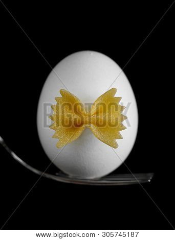 White Chicken Eggwhite Chicken Egg On A Fork With A Bow Of Pasta On A Black Background