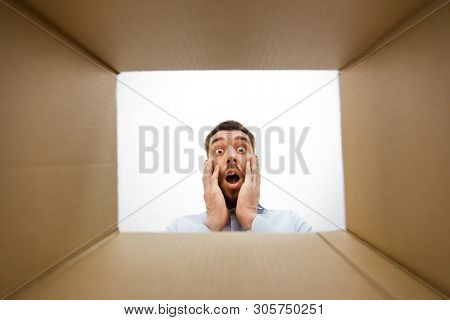 emotions, delivery and surprise concept - shocked man looking into open parcel box, from below