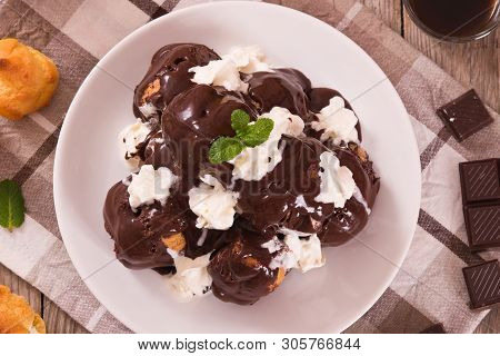 Chocolate Profiteroles With Whipped Cream On White Dish.