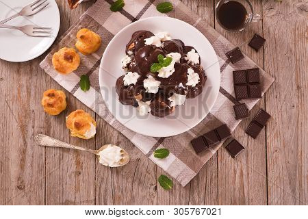 Chocolate Profiteroles With Whipped Cream On White Dish.