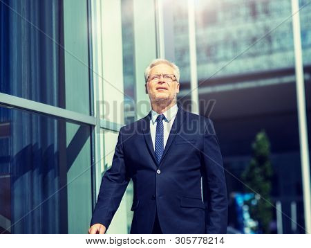 business and people concept - senior businessman walking along city street