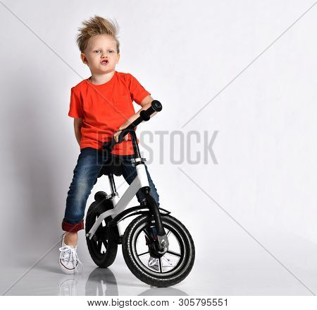 Young Kid Boy In Orange T-shirt And Blue Jeans Imagines He Rides Fast His New Cool Bicycle Without P