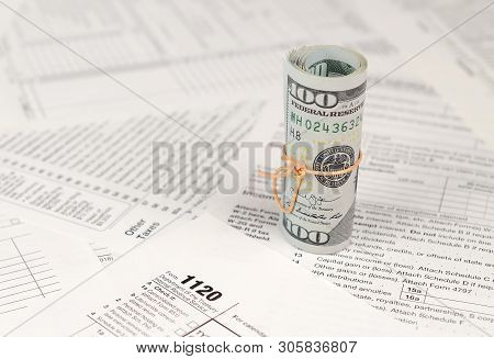 1120 U.s. Corporation Income Tax Return Form With Roll Of American Dollar Banknotes