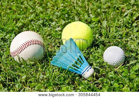 Sports Equipment (baseball, Tennis, Badminton, Golf) Lying In The Green Grass
