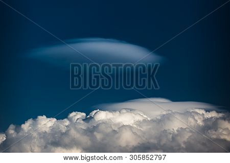 Rare Lenticular Cloud Altocumulus Lenticularis On Top Of A Cumulus Cloud In Front Of A Blue Sky