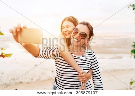 Two Caucasian Girlfriends Hugging And Posing For Selfie On The Sea Side Using Smartphone. Careless V