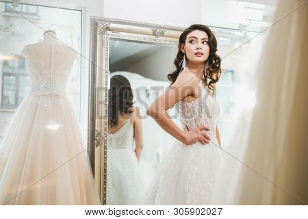 Beautifu bride choosing wedding dress in a wedding salon