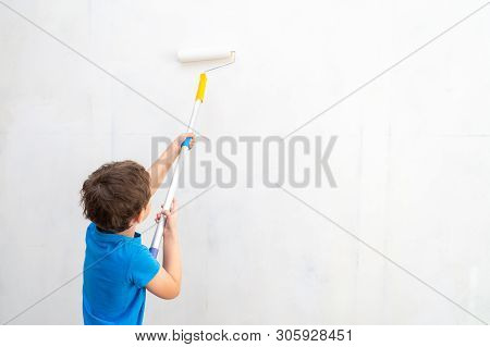 Child Rolls The Roller In The Paint On The Wall. Finishing Work In The Premises Of The Artist Paints