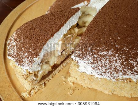 Banoffee Pie Cake With Bananas In Layers Of Whipped Cream, Chocolate, Caramel And Toffee On Wooden P