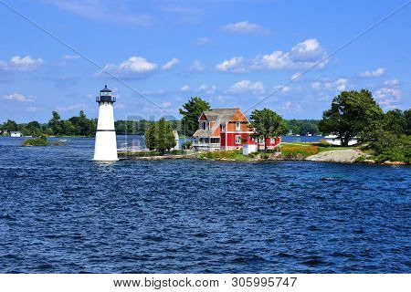 Cottage With Lighthouse On One Of The Thousand Islands During Summer, New York State, Usa