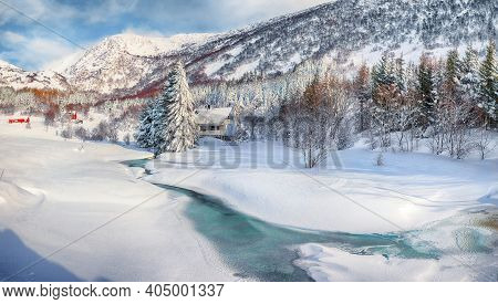 Awesome Winter Scenery With Frozen River With Wooden Houses And Snow Covered Pine Trees Near Valberg