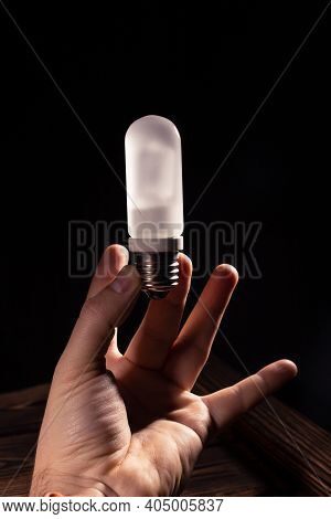 White Frosted Flash Pilot Lamp In Hand. Studio Photo In Hard Light.