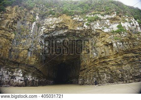 Catlins New Zealand - February 24 2015; Tourist Walking Into  Weathered Rock Face  Entrance To Black