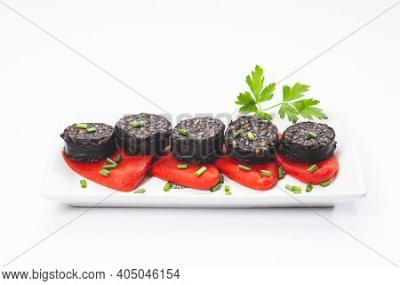 Slices Of Spanish Black Pudding On Piquillo Peppers In White Plate On White Background. Spanish Tapa