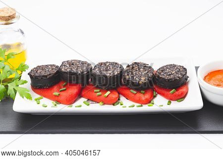 Slices Of Spanish Black Pudding On Piquillo Peppers In White Plate On White Background. Spanish Tapa