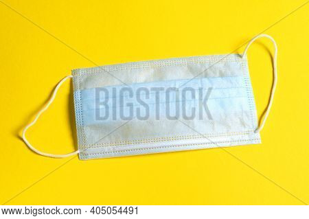Medical Hygienic Protective Face Ear-loop Mask On Yellow Background. Prevent Virus Infection