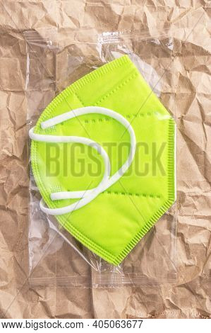 Kn95 Green Medical Respiratory Mask In Plastic Packaging On An Abstract Background Of Crumpled Kraft