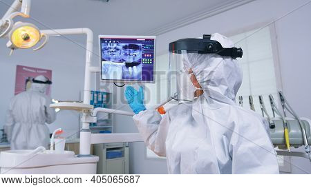 Patient Pov Of Dentist In Coverall Talking About Mouth Hygine Showing X-ray On Monitor. Stomatology 