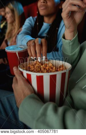 Close Up Of Red With White Basket Of Popcorn. Young Couple Are Taking Popcorn Out Of Basket While Wa