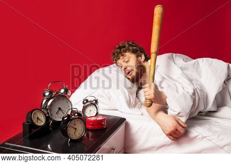 Dreams. Man Wakes Up At His Bed On Red Background And Hes Mad At Clocks Ringing, Switches It Off Wit