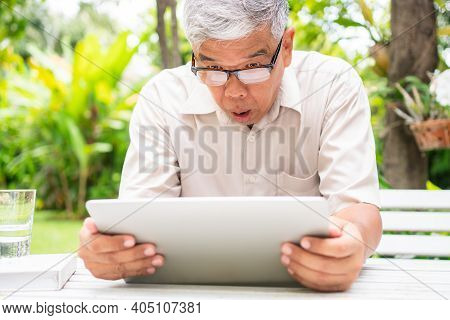 Portrait Of An Old Elderly Asian Man Is Holding A Computer Laptop And Surprised After Got Some Email