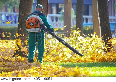 Working In The Park Removes Leaves With A Blower